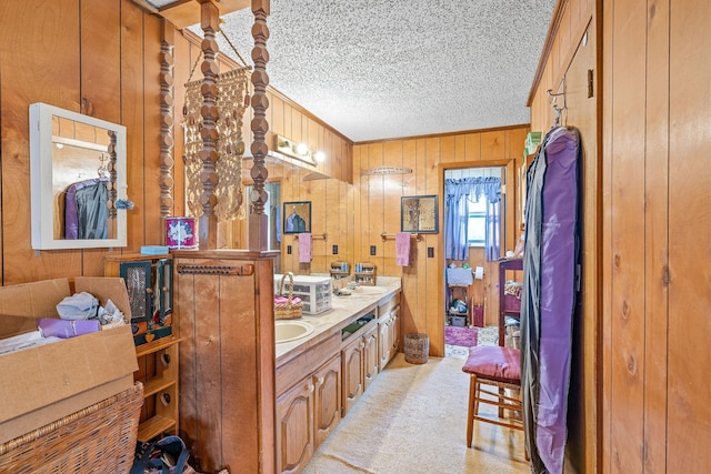 bathroom with crown molding, vanity, a textured ceiling, and wood walls