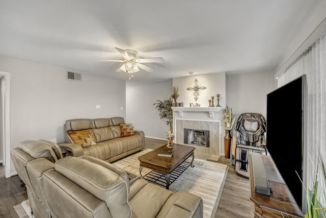 living room with ceiling fan, a fireplace, and light hardwood / wood-style floors