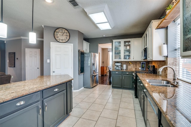 kitchen featuring light tile patterned flooring, appliances with stainless steel finishes, white cabinetry, sink, and hanging light fixtures