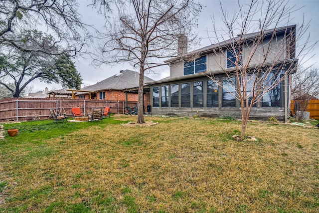 back of house featuring a yard, a sunroom, and an outdoor fire pit