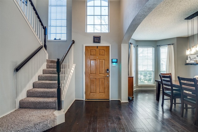 entryway with dark wood-type flooring, a textured ceiling, and a high ceiling