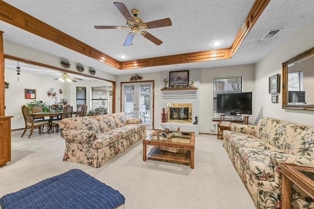 living area with light carpet, a tray ceiling, a textured ceiling, and a wealth of natural light