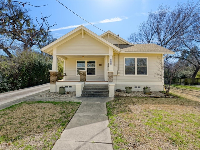 bungalow-style house featuring a porch, crawl space, a shingled roof, and a front lawn