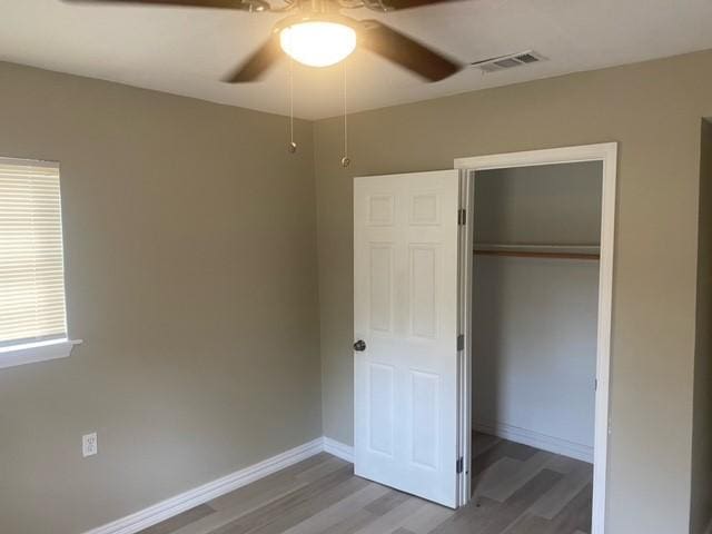 unfurnished bedroom featuring hardwood / wood-style flooring, a closet, and ceiling fan