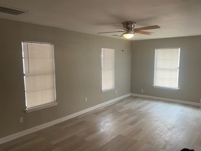 spare room featuring plenty of natural light, hardwood / wood-style floors, and ceiling fan