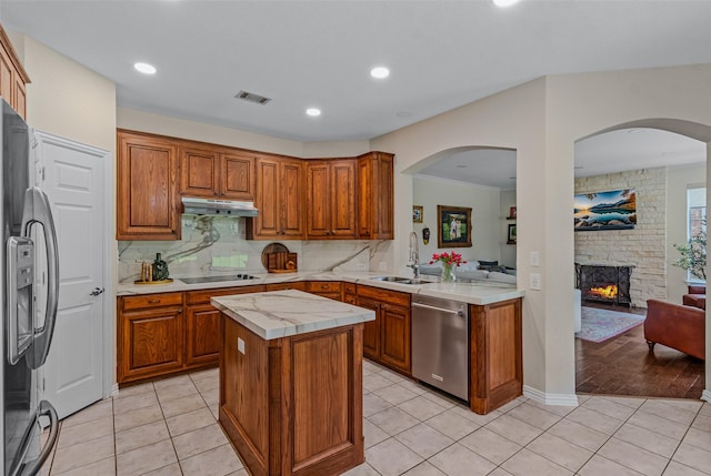 kitchen with light tile patterned flooring, sink, tasteful backsplash, a kitchen island, and black appliances