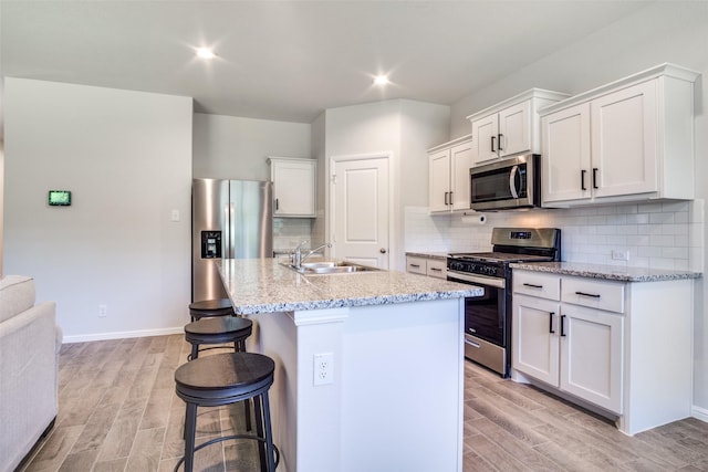 kitchen featuring appliances with stainless steel finishes, sink, an island with sink, and white cabinets