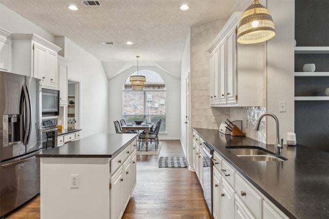 kitchen featuring sink, a center island, hanging light fixtures, stainless steel appliances, and white cabinets