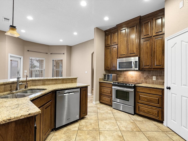 kitchen featuring sink, hanging light fixtures, light tile patterned floors, stainless steel appliances, and backsplash