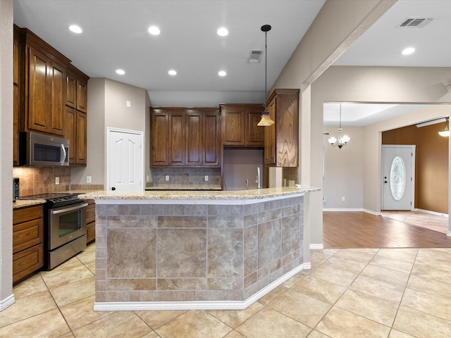 kitchen featuring hanging light fixtures, light tile patterned floors, light stone countertops, and appliances with stainless steel finishes