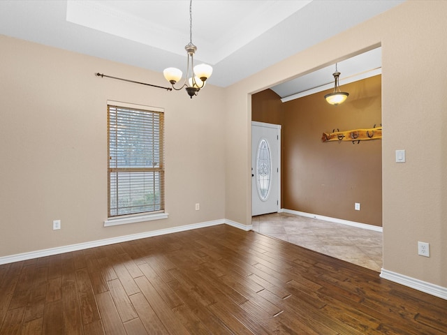 interior space featuring an inviting chandelier, a raised ceiling, and hardwood / wood-style floors