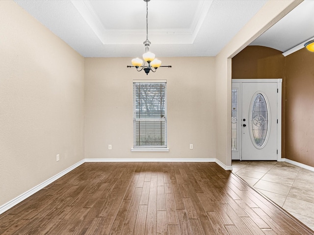 foyer featuring hardwood / wood-style flooring, a tray ceiling, and a notable chandelier