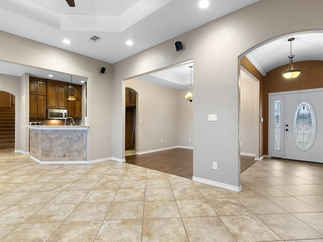 interior space featuring decorative light fixtures, ornamental molding, light tile patterned floors, ceiling fan, and a tray ceiling