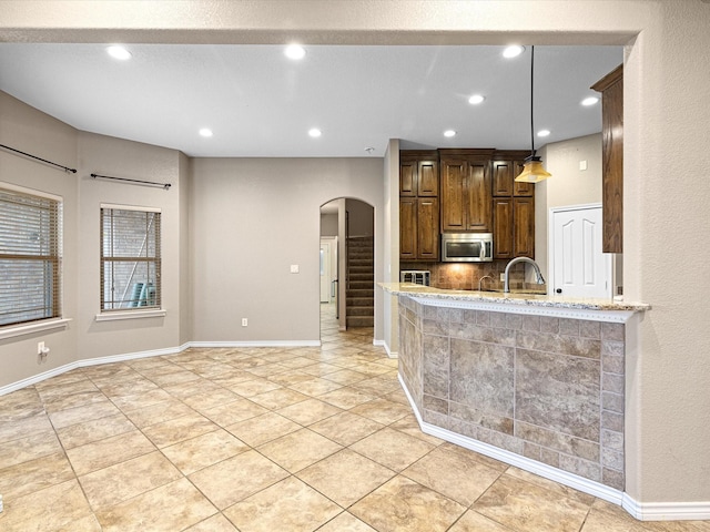 kitchen featuring light tile patterned floors, decorative light fixtures, light stone countertops, and kitchen peninsula