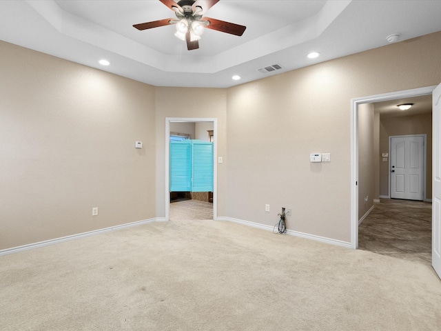 carpeted empty room featuring a raised ceiling and ceiling fan