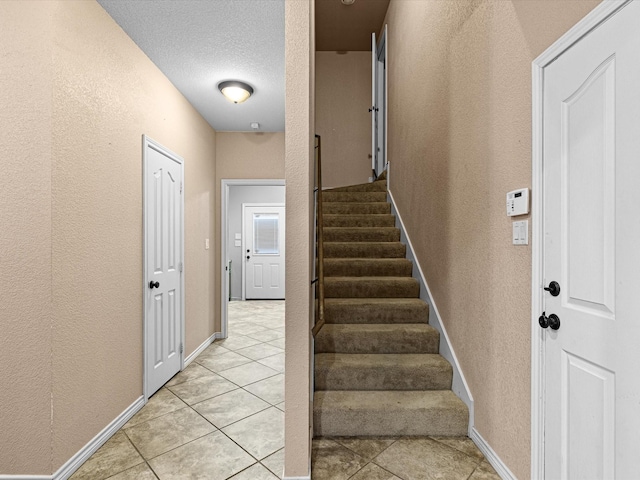 staircase featuring tile patterned floors and a textured ceiling