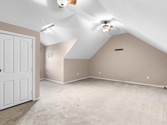 additional living space featuring ceiling fan, lofted ceiling, light carpet, and a textured ceiling