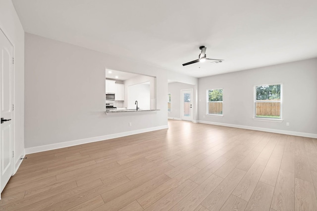 unfurnished living room with ceiling fan, sink, and light hardwood / wood-style floors