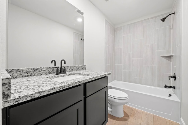 full bathroom with vanity, tiled shower / bath combo, wood-type flooring, and toilet