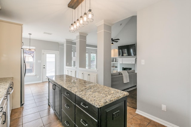 kitchen featuring decorative light fixtures, light stone countertops, ceiling fan, and a kitchen island