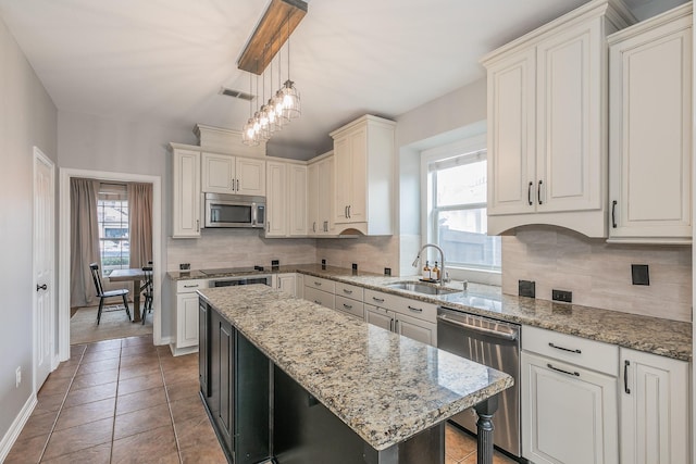 kitchen featuring sink, backsplash, stainless steel appliances, a kitchen island, and decorative light fixtures