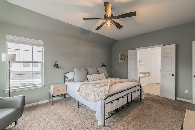 bedroom with ensuite bath, vaulted ceiling, light colored carpet, and ceiling fan