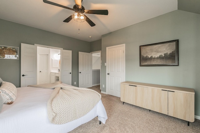 bedroom featuring vaulted ceiling, light colored carpet, ceiling fan, and ensuite bath