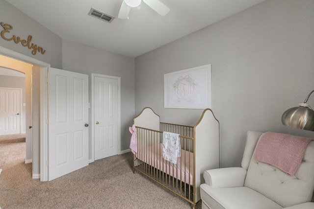 carpeted bedroom with a nursery area and ceiling fan