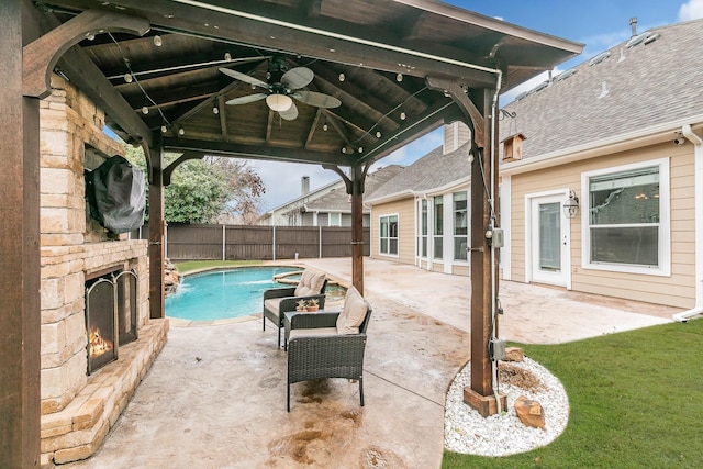 view of swimming pool with pool water feature, ceiling fan, a patio area, and an outdoor stone fireplace