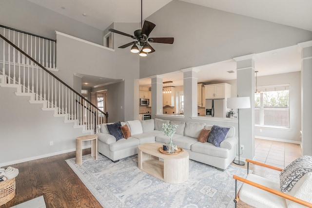 living room featuring hardwood / wood-style flooring, ceiling fan, high vaulted ceiling, and ornate columns