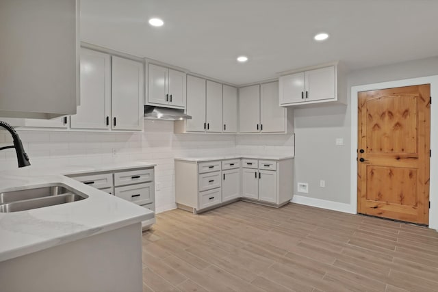 4101 Cole St, Fort Worth, TX 76115 - kitchen with a sink, under cabinet range hood, decorative backsplash, light stone countertops, and white cabinetry