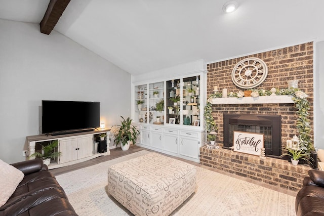 living room with a brick fireplace, vaulted ceiling with beams, and light hardwood / wood-style flooring