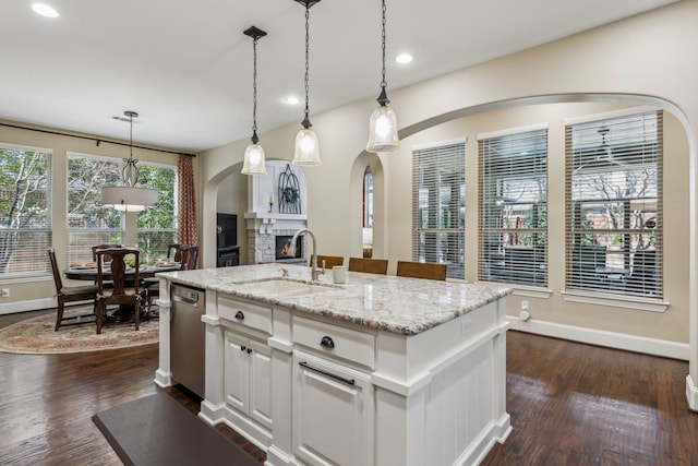 kitchen featuring dark wood finished floors, a fireplace, a sink, and stainless steel dishwasher