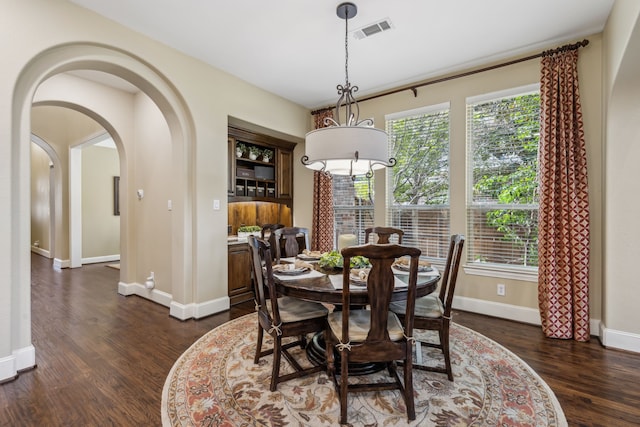 dining room with baseboards, visible vents, arched walkways, and dark wood-style flooring