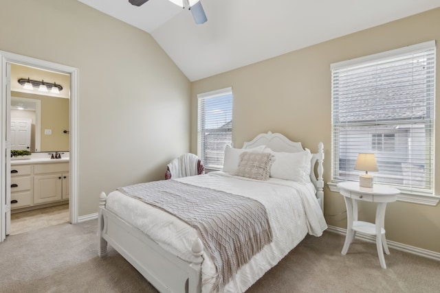 bedroom featuring baseboards, light colored carpet, ensuite bath, vaulted ceiling, and a sink