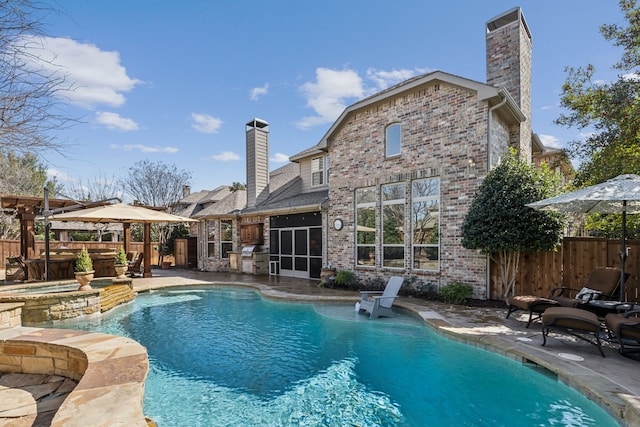 back of house with a patio area, brick siding, fence, and a chimney