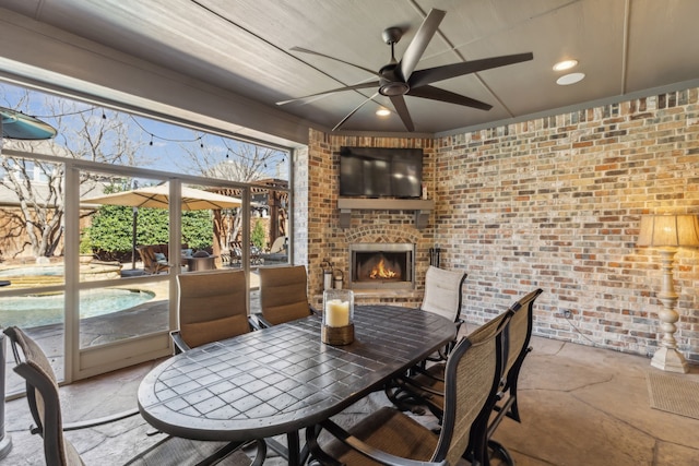 dining space with an outdoor brick fireplace, recessed lighting, ceiling fan, and brick wall