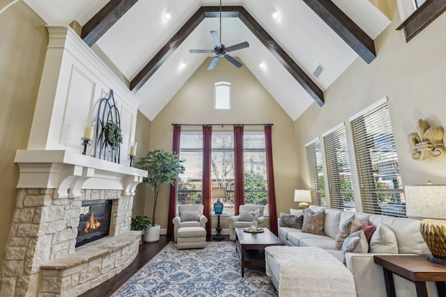 living area featuring beam ceiling, a fireplace, visible vents, wood finished floors, and high vaulted ceiling