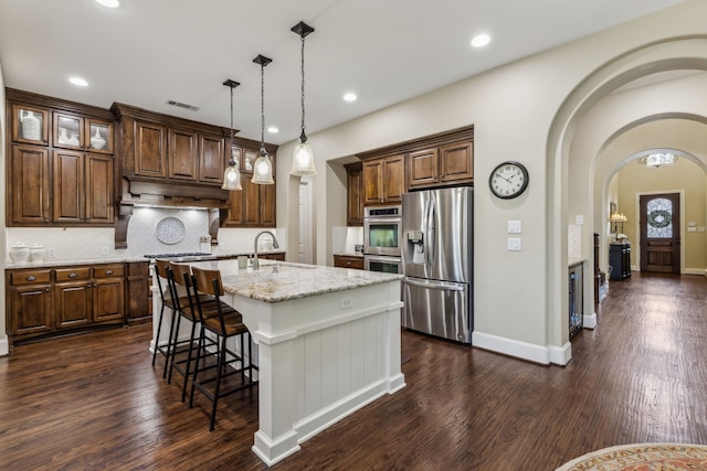 kitchen with stainless steel appliances, dark wood finished floors, a sink, and under cabinet range hood