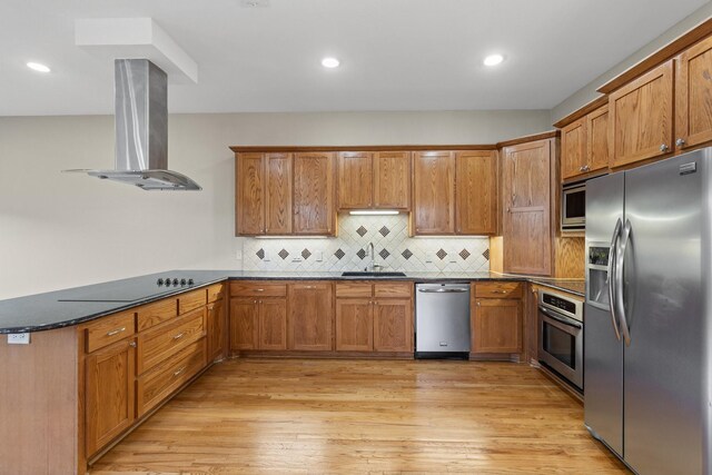 kitchen with brown cabinets, stainless steel appliances, a sink, island range hood, and light wood-type flooring