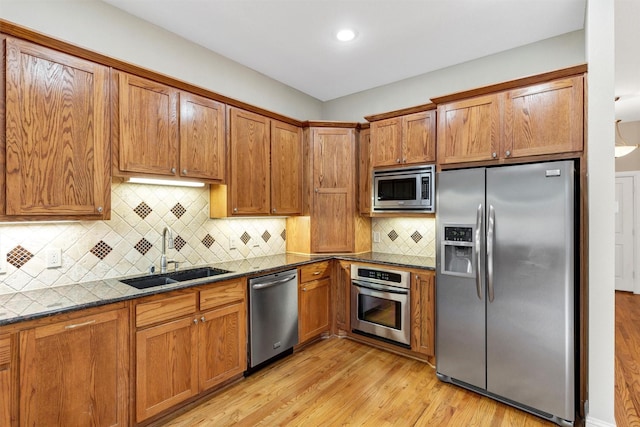 6039 Reiger Ave, Dallas, TX 75214 - kitchen featuring tasteful backsplash, a sink, brown cabinets, light wood-style flooring, and appliances with stainless steel finishes