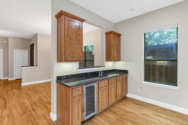 6039 Reiger Ave, Dallas, TX 75214 - kitchen with dark stone counters, baseboards, beverage cooler, and light wood-type flooring