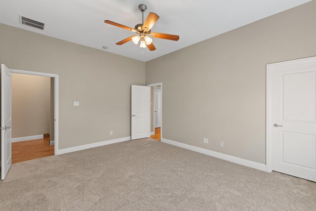 carpeted empty room featuring ceiling fan, visible vents, and baseboards