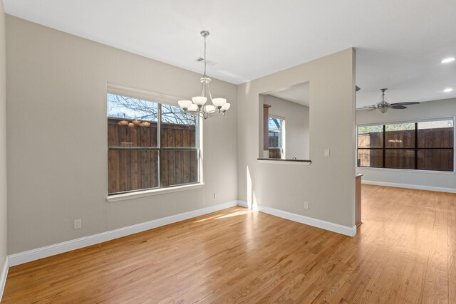 spare room with an inviting chandelier, light wood-style flooring, visible vents, and baseboards