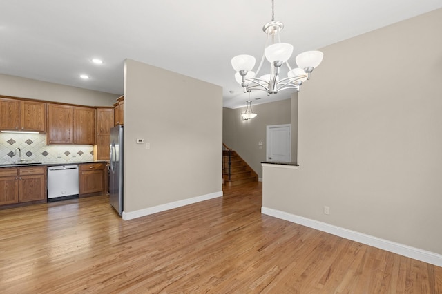 unfurnished room with ceiling fan with notable chandelier, plenty of natural light, wood finished floors, and baseboards