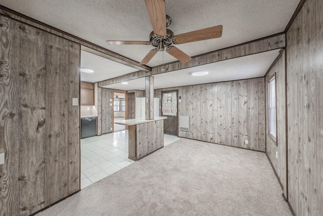 kitchen with light carpet, a textured ceiling, white refrigerator, wooden walls, and black dishwasher