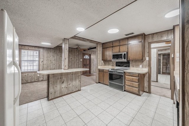 kitchen with a breakfast bar area, light carpet, electric range, white refrigerator, and wooden walls