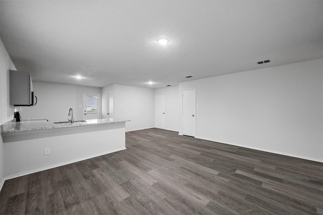 unfurnished living room featuring sink, dark wood-type flooring, and a textured ceiling