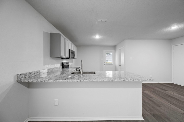 kitchen featuring sink, a textured ceiling, appliances with stainless steel finishes, dark hardwood / wood-style flooring, and kitchen peninsula