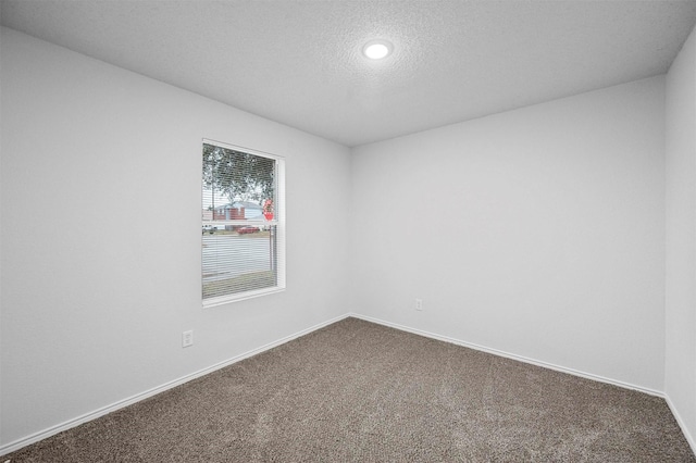 unfurnished room with a textured ceiling and carpet flooring